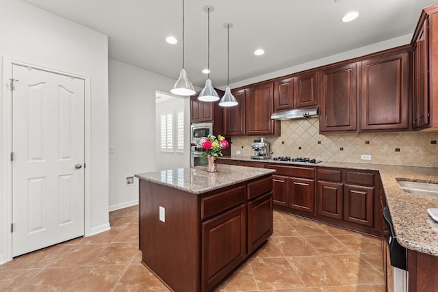 kitchen with a center island, decorative light fixtures, tasteful backsplash, appliances with stainless steel finishes, and under cabinet range hood