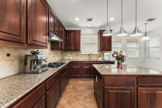 kitchen with visible vents, a sink, under cabinet range hood, stainless steel gas stovetop, and backsplash