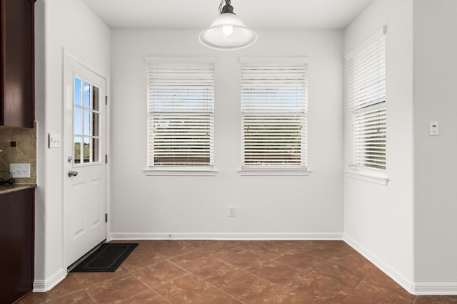 doorway to outside featuring dark tile patterned flooring and baseboards