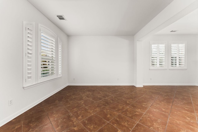 tiled spare room with baseboards, visible vents, and a healthy amount of sunlight