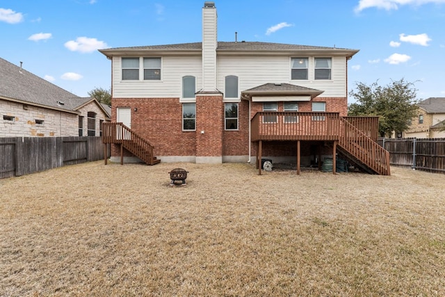 rear view of house with an outdoor fire pit, a fenced backyard, brick siding, stairs, and a wooden deck