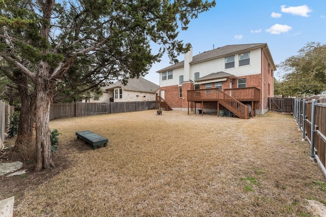 back of property featuring a lawn, a fenced backyard, stairs, a wooden deck, and brick siding