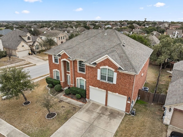 view of front of house featuring driveway, a garage, a shingled roof, fence, and brick siding