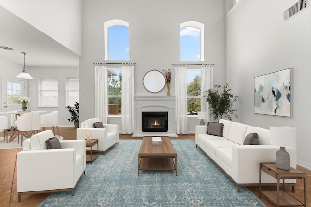 living room featuring visible vents, plenty of natural light, and a high ceiling