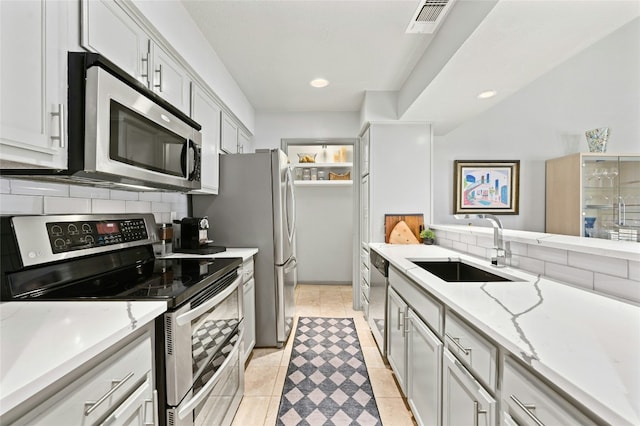 kitchen with tasteful backsplash, visible vents, stainless steel appliances, a sink, and light tile patterned flooring