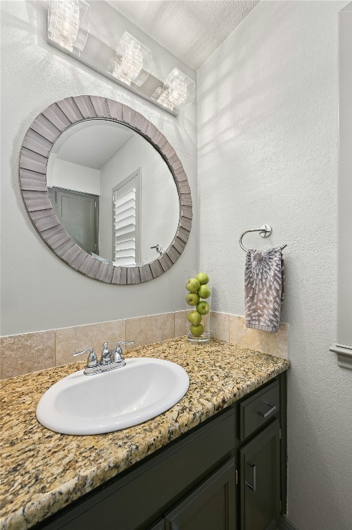 bathroom with a textured ceiling, a textured wall, and vanity