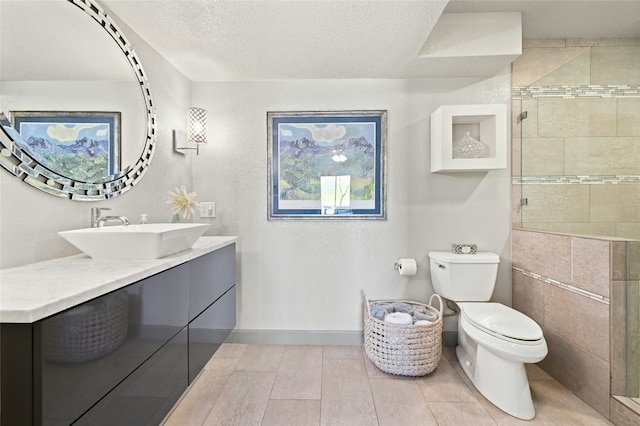 full bathroom with toilet, a shower stall, a textured ceiling, and vanity