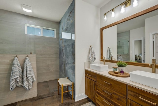 bathroom featuring double vanity, walk in shower, a sink, and wood finished floors