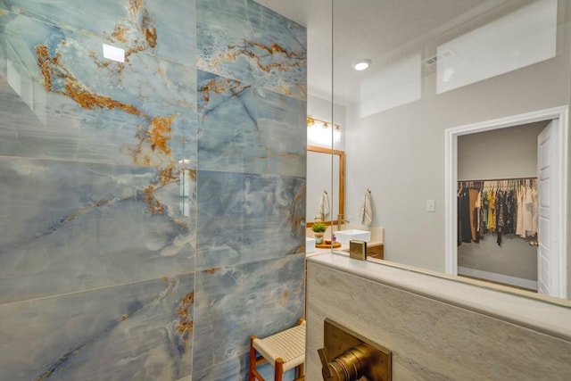 bathroom featuring a walk in shower, a walk in closet, and vanity