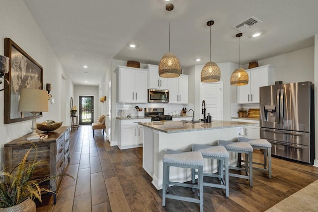 kitchen with dark wood-style floors, visible vents, appliances with stainless steel finishes, and backsplash