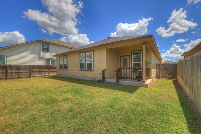 back of house featuring a gate, a fenced backyard, and a lawn