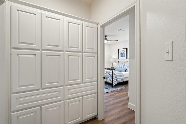 hall featuring dark wood-type flooring and visible vents