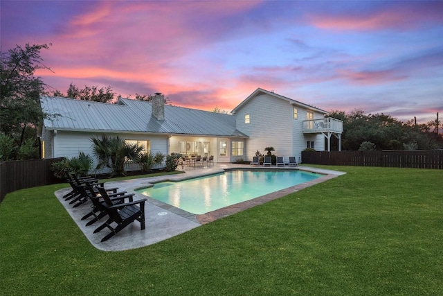 pool at dusk with a fenced in pool, fence, a lawn, and a patio