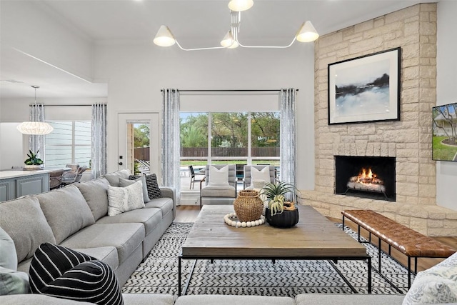 living area featuring a stone fireplace, wood finished floors, and a healthy amount of sunlight