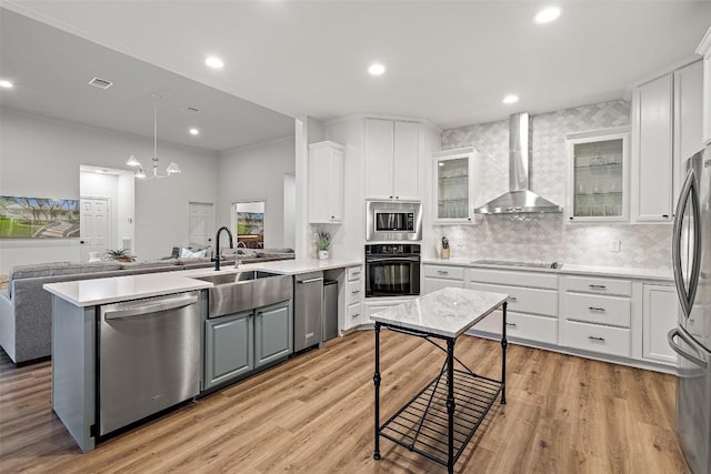 kitchen featuring visible vents, white cabinetry, a sink, wall chimney range hood, and black appliances