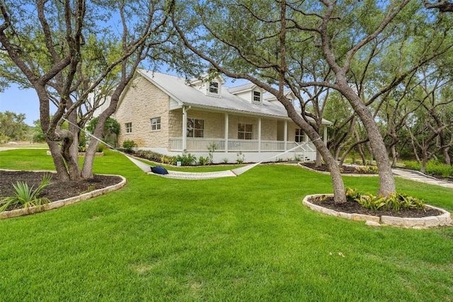 view of front of house featuring stone siding, metal roof, a porch, and a front yard