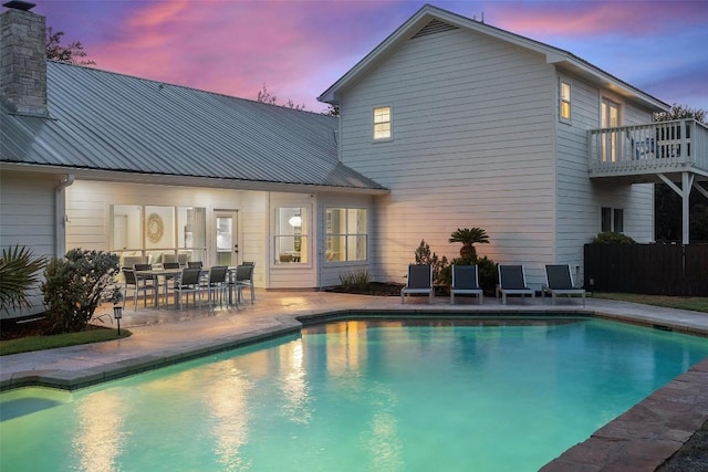 pool at dusk featuring a patio area and an outdoor pool