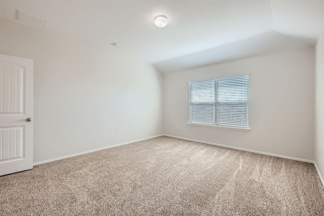 carpeted empty room featuring visible vents, vaulted ceiling, and baseboards