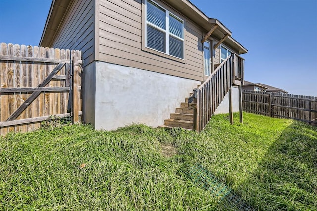 view of home's exterior with fence, stairway, and a lawn