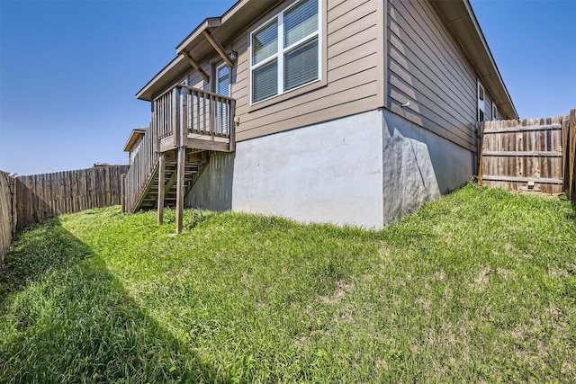 view of side of property featuring stairway, a lawn, and a fenced backyard