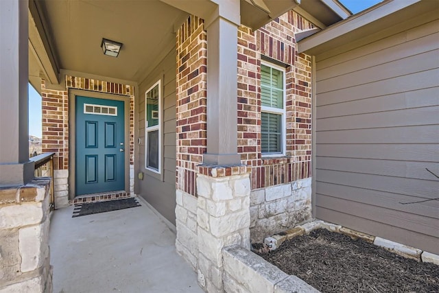 entrance to property with covered porch and brick siding