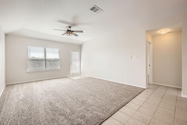 empty room with visible vents, a ceiling fan, light carpet, light tile patterned flooring, and baseboards