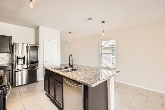 kitchen with light tile patterned floors, stainless steel appliances, visible vents, hanging light fixtures, and a sink