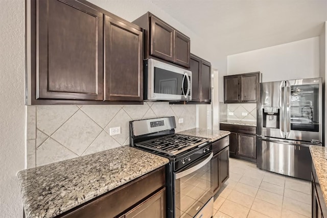 kitchen featuring stainless steel appliances, light stone counters, and dark brown cabinets