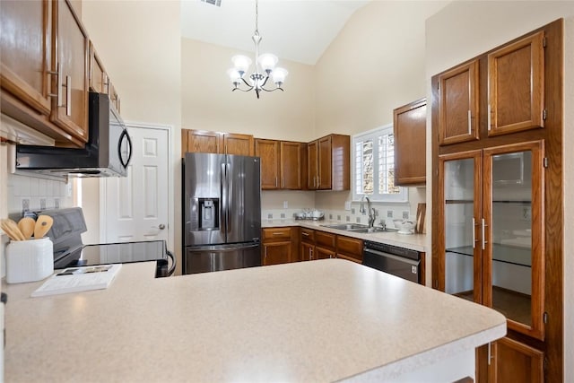 kitchen featuring appliances with stainless steel finishes, light countertops, a sink, and a peninsula