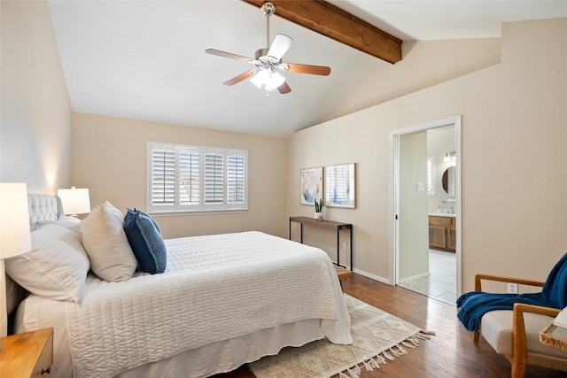 bedroom with lofted ceiling with beams, ceiling fan, wood finished floors, baseboards, and ensuite bath