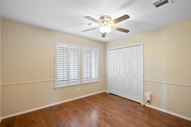 unfurnished bedroom with a closet, wood finished floors, visible vents, and baseboards