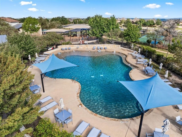 community pool with a patio area and fence