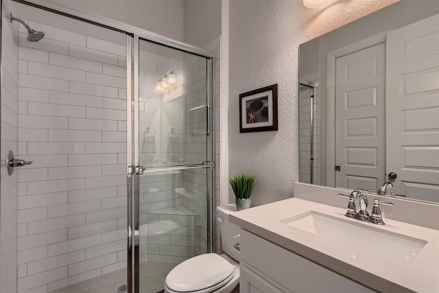 full bathroom with a textured wall, vanity, a shower stall, and toilet