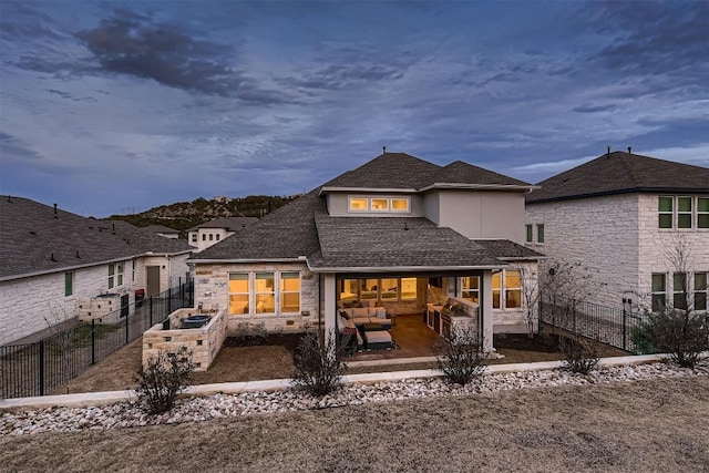 rear view of house featuring stone siding, a patio area, a fenced backyard, and stucco siding