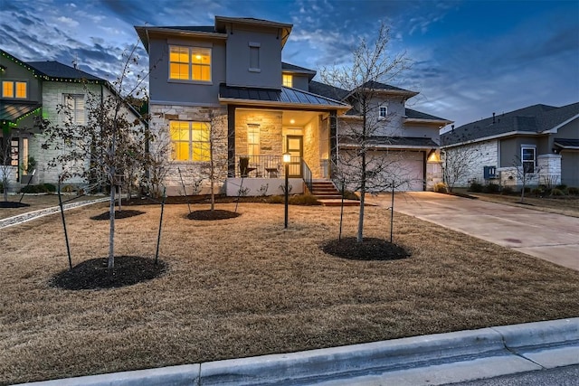 view of front of house featuring concrete driveway, stone siding, metal roof, an attached garage, and a standing seam roof