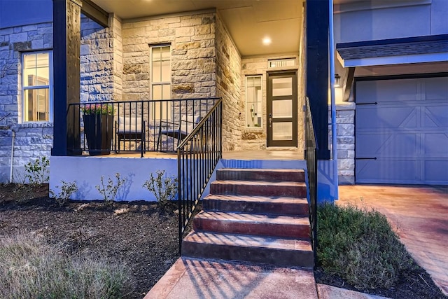 entrance to property with covered porch, stone siding, and a garage