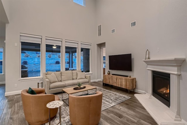 living room featuring a glass covered fireplace, visible vents, and wood finished floors