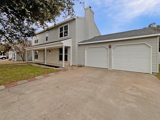 view of front of house featuring brick siding, a chimney, a front yard, a garage, and driveway