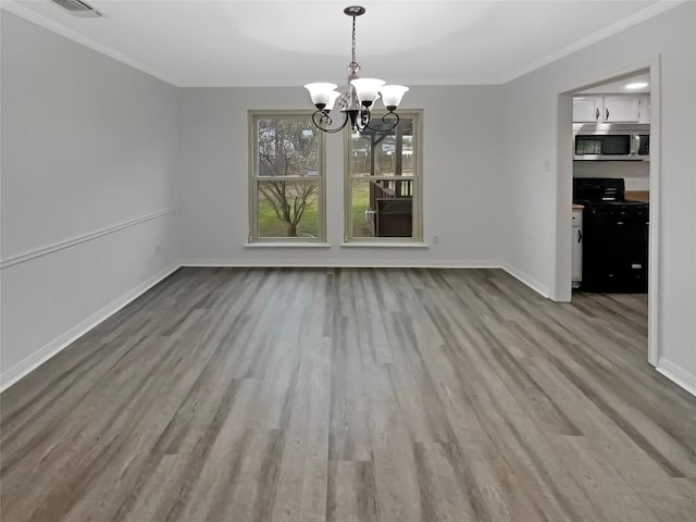 unfurnished dining area with baseboards, a notable chandelier, wood finished floors, and crown molding