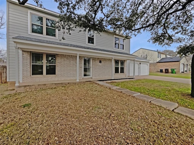 view of front of home with driveway, an attached garage, a front lawn, and brick siding