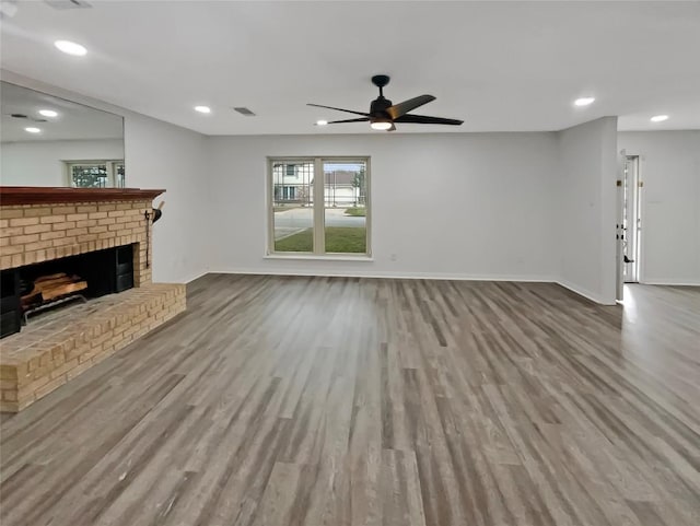 unfurnished living room with recessed lighting, a brick fireplace, baseboards, and wood finished floors