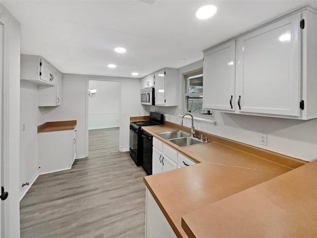 kitchen with recessed lighting, light wood-style flooring, a sink, black appliances, and baseboards