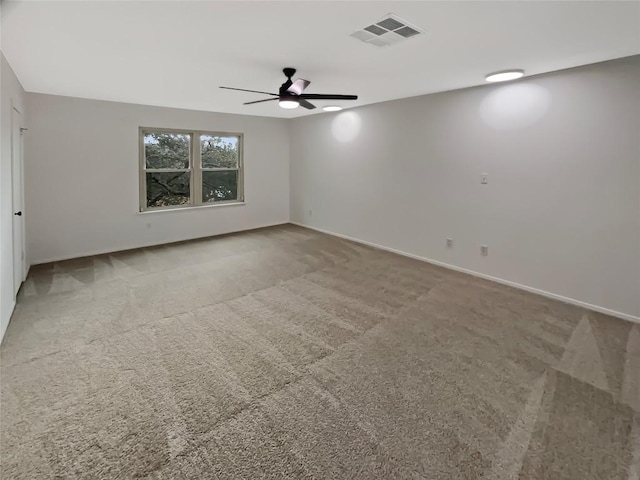 carpeted empty room with ceiling fan, visible vents, and baseboards