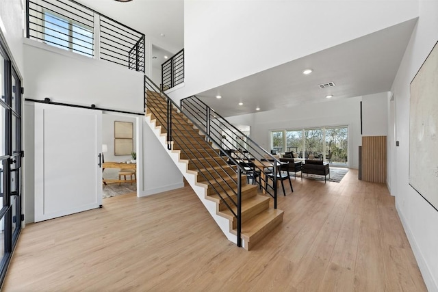 entryway featuring a barn door, baseboards, stairway, wood finished floors, and a high ceiling