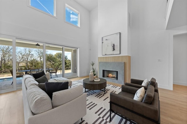 living area featuring a healthy amount of sunlight, light wood-style floors, a lit fireplace, and baseboards