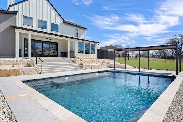 pool with a ceiling fan, a yard, fence, and stairs