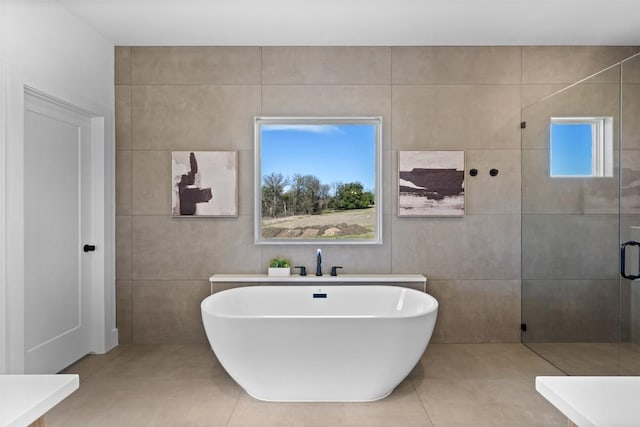 full bath featuring tile patterned flooring, a shower stall, a freestanding bath, and tile walls