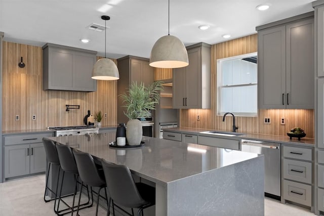 kitchen with gray cabinetry, a sink, visible vents, stainless steel dishwasher, and a center island