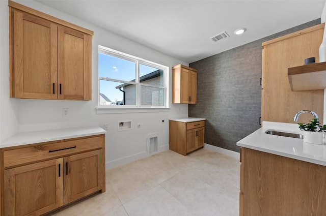 kitchen featuring wallpapered walls, baseboards, visible vents, light countertops, and a sink