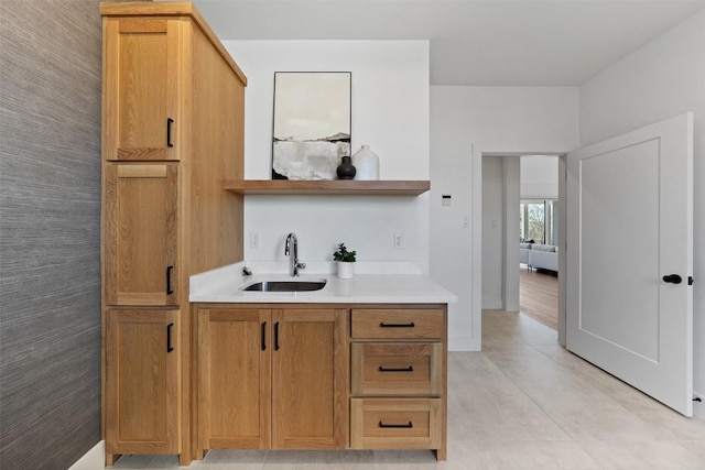 bar featuring baseboards and a sink